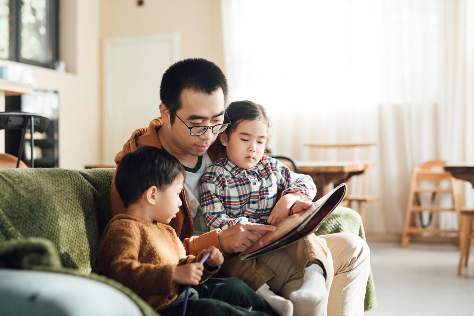 Father reading with two children on a sofa